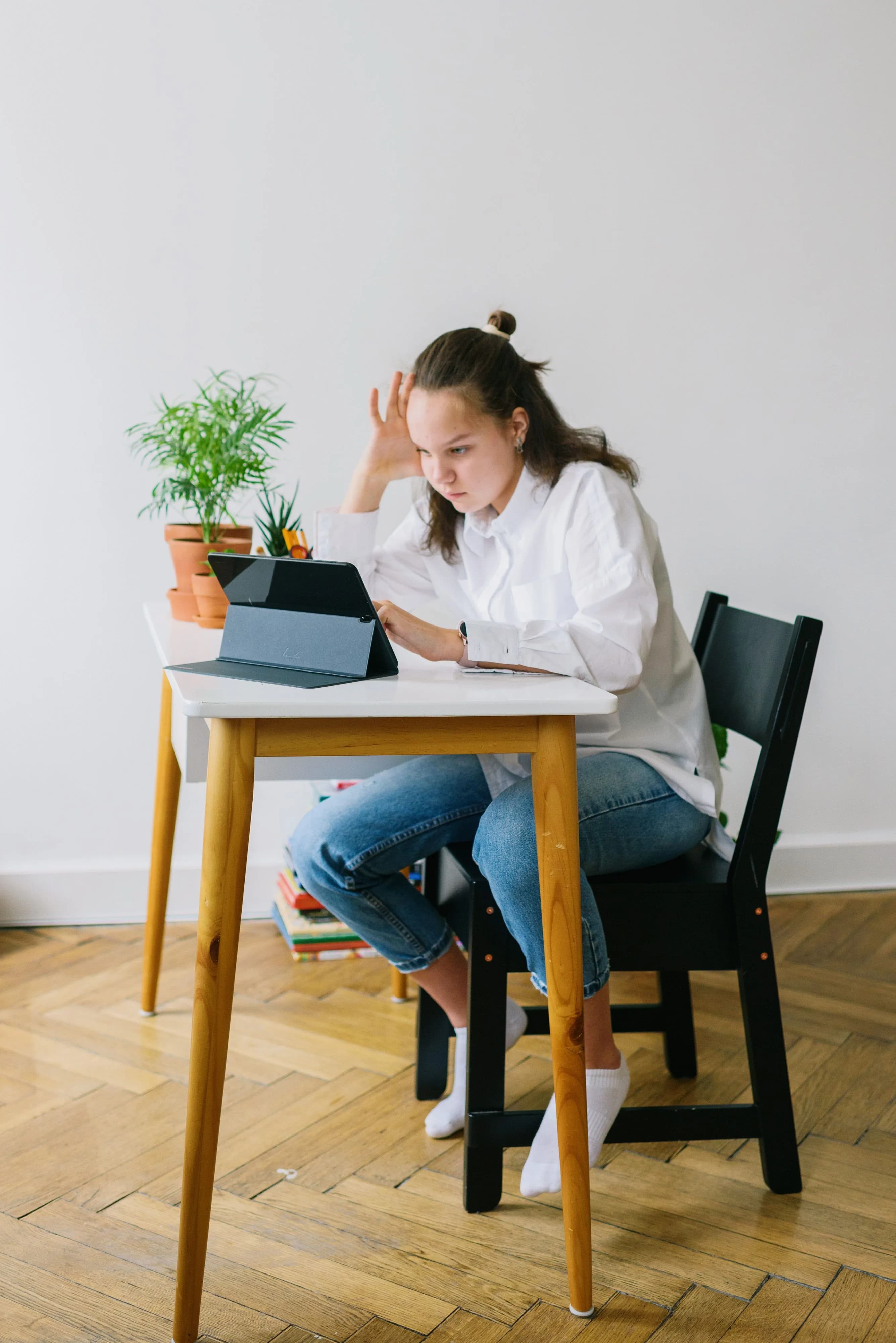Uczennica ucząca się w domu przy biurku z tabletem